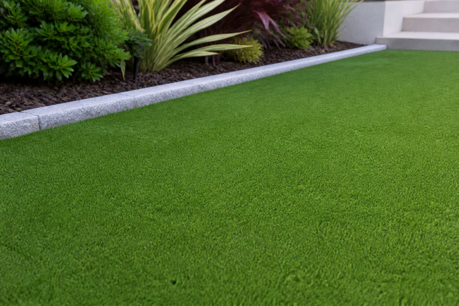 Even green artificial turf beside a landscaped border
